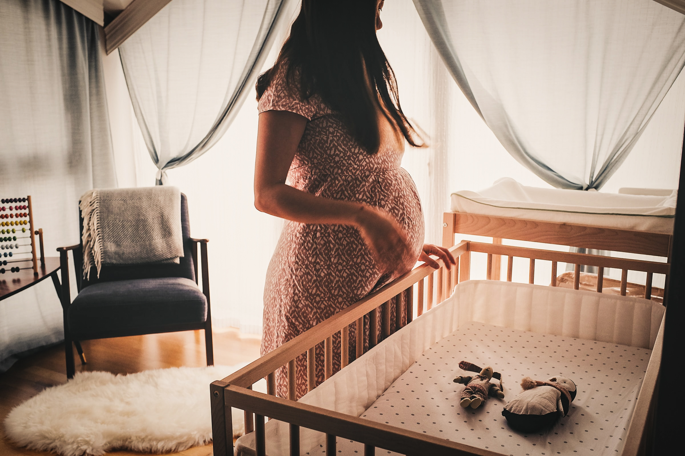 Femme enceinte devant une bassinette dans une chambre de bébé