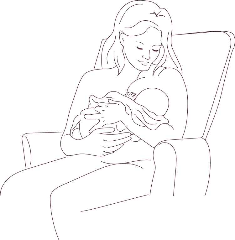 Mère assise dans un fauteuil et berçant son bébé qu'elle tient dans ses bras.